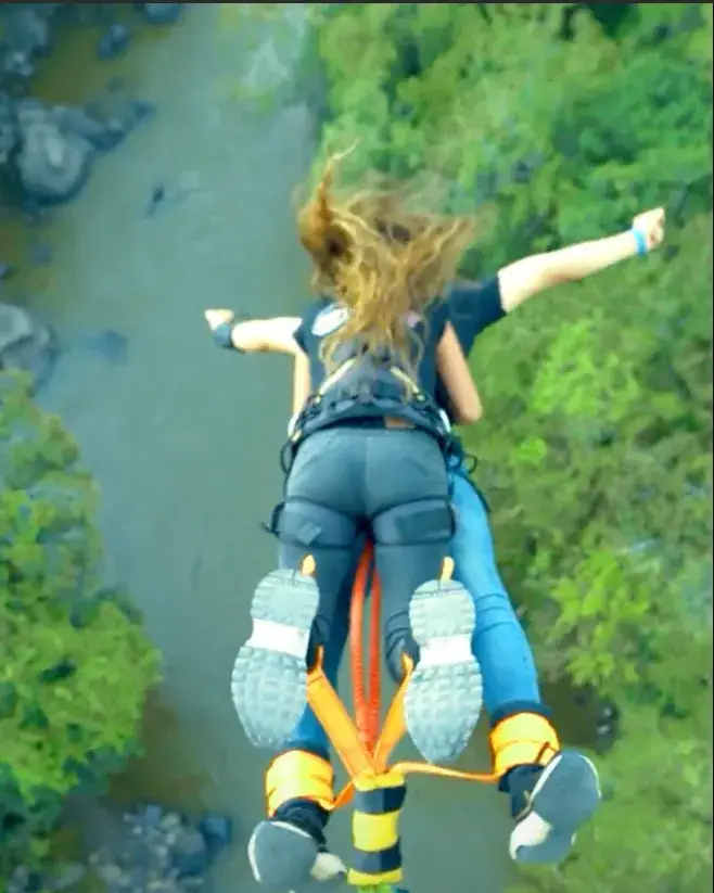 Persona en caída libre amarrada al cable del bungee, con el río Fonce abajo