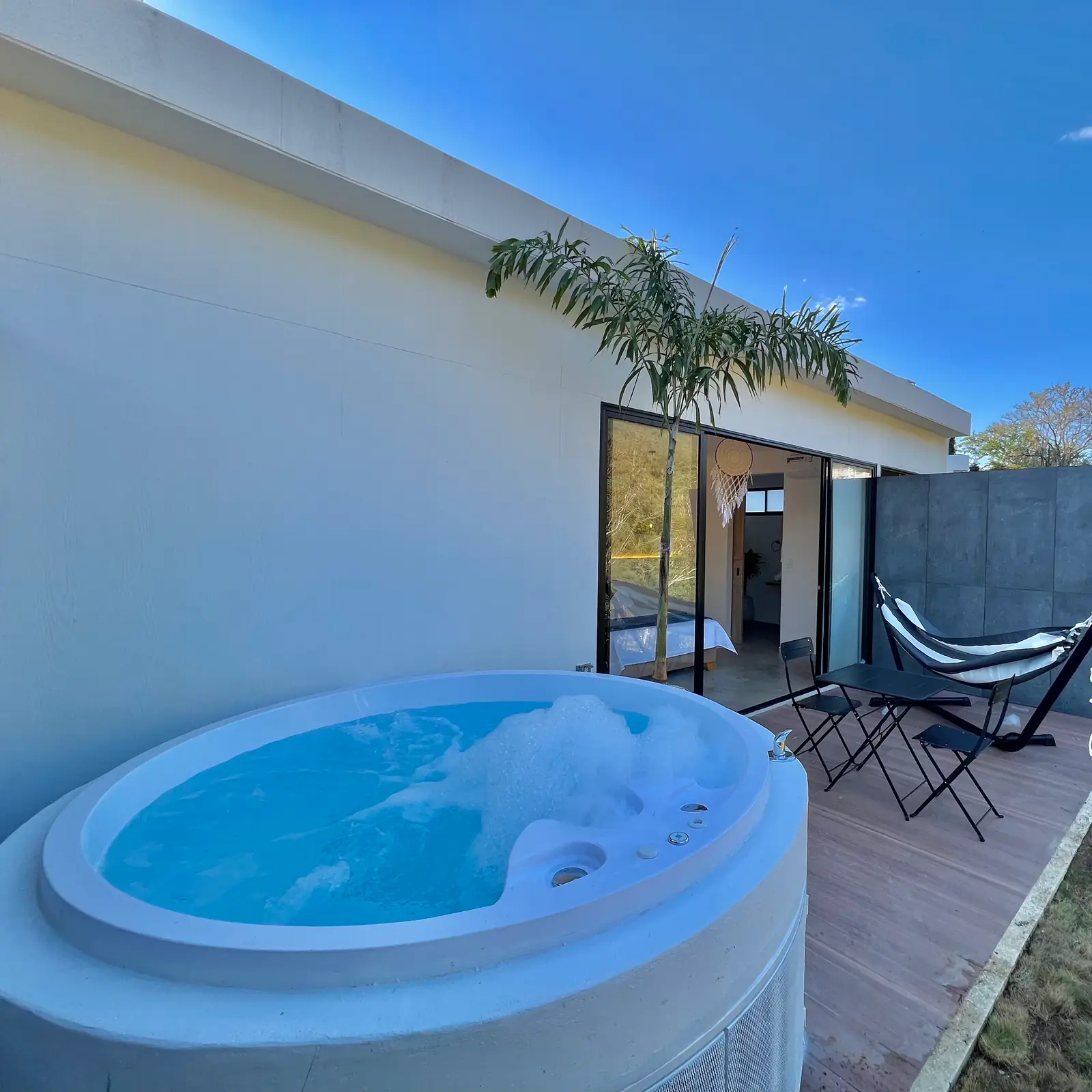 Jacuzzi redondo lleno de agua azul en la terraza de madera de la cabaña doble, bajo el cielo despejado