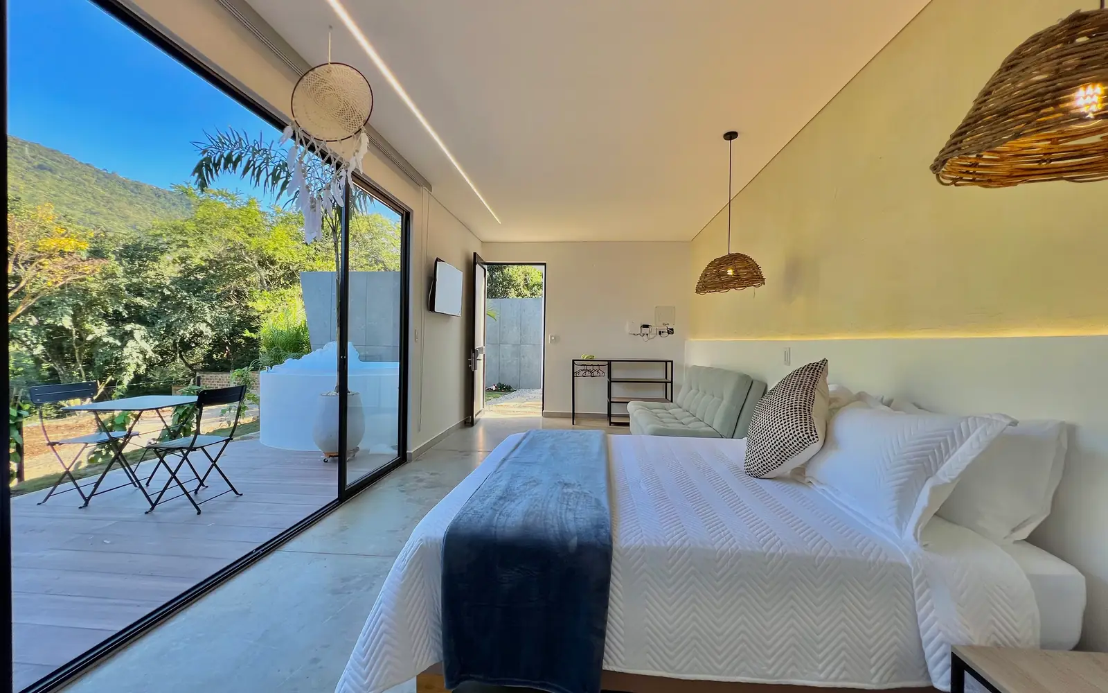 La cabaña doble por dentro: cama, lámparas de fibra y una pared de vidrio que mira a la montaña