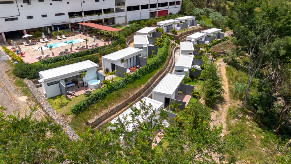 Las cabañas con jacuzzi en primer plano y la piscina al fondo, desde el dron