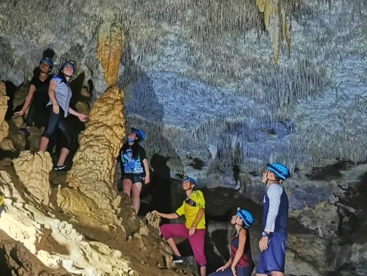 Visitantes con casco y linterna avanzan entre estalactitas dentro de la cueva de la Vaca