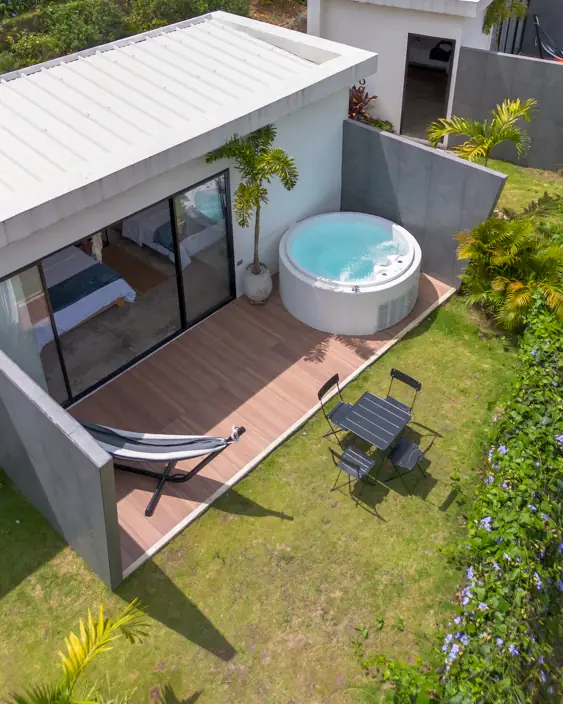 Terraza de madera de una cabaña con su jacuzzi y la hamaca, vista desde el dron